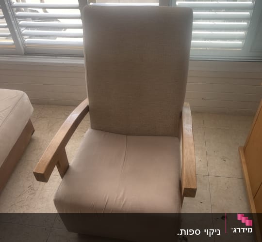 כיסא מרופד עם כתמים על הרצפה ליד חלון